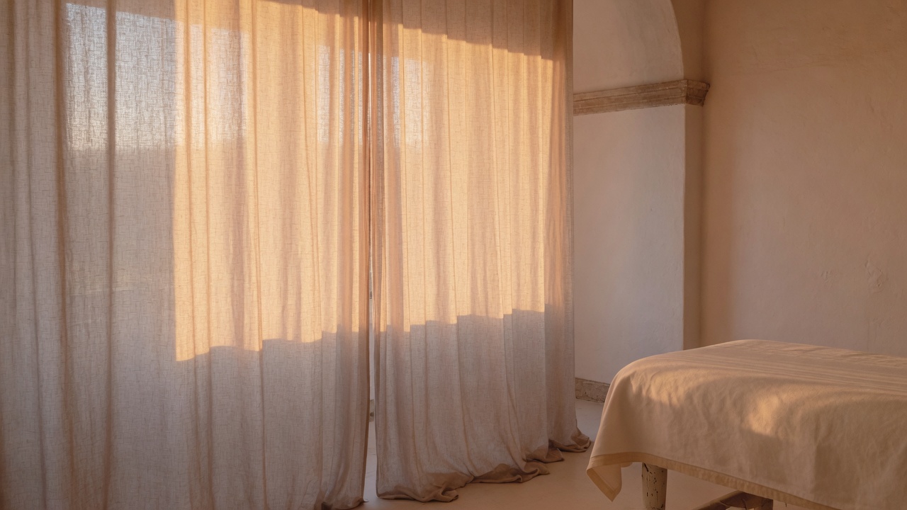 Sheer linen curtains filling a treatment room with late afternoon light.